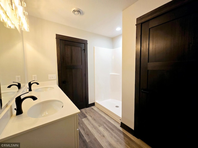 2001 Essler Dr, Saint Peter, MN 56082 - bathroom featuring double vanity, wood finished floors, a shower, and recessed lighting