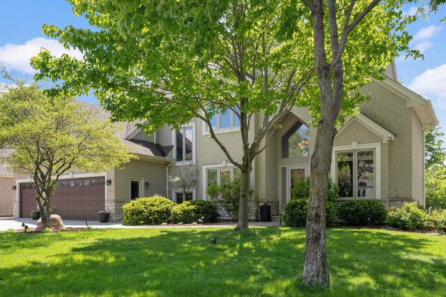 3583 Woodland Trl, Eagan, MN 55123 - view of property hidden behind natural elements with stucco siding, stone siding, a front lawn, and a garage