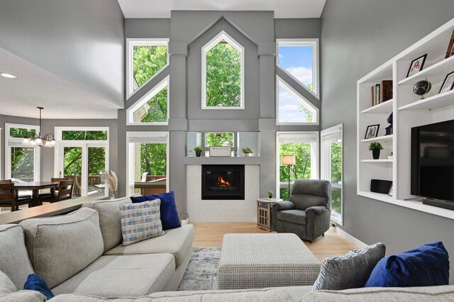 3583 Woodland Trl, Eagan, MN 55123 - living room with a high ceiling, a chandelier, a glass covered fireplace, and wood finished floors
