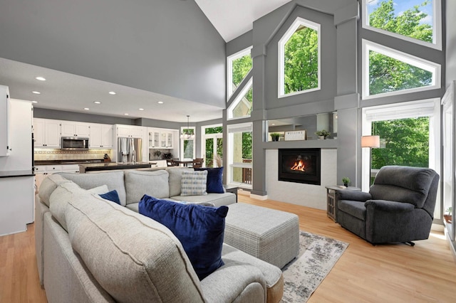 3583 Woodland Trl, Eagan, MN 55123 - living room featuring high vaulted ceiling, a glass covered fireplace, light wood-type flooring, and recessed lighting
