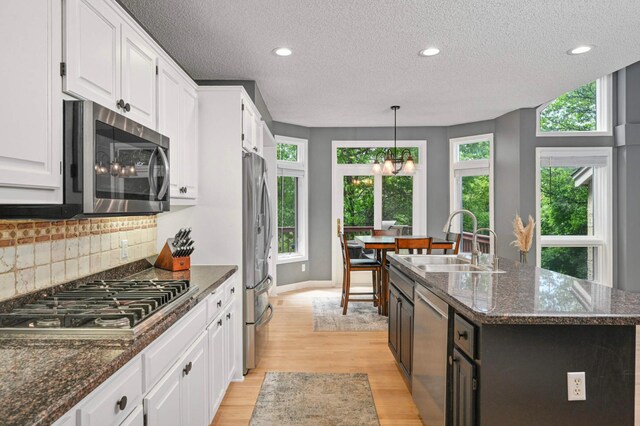 3583 Woodland Trl, Eagan, MN 55123 - kitchen with appliances with stainless steel finishes, light wood-style flooring, white cabinets, tasteful backsplash, and a textured ceiling