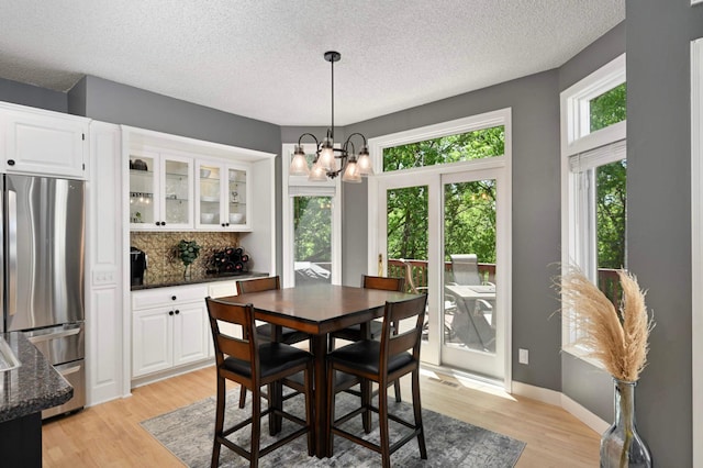 3583 Woodland Trl, Eagan, MN 55123 - dining space featuring light wood finished floors, a textured ceiling, and a chandelier
