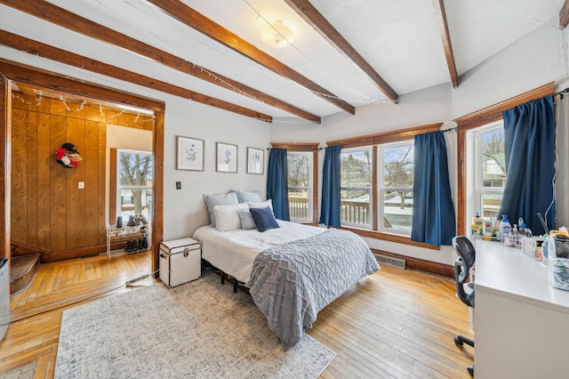 216 Elm St, River Falls, WI 54022 - bedroom with light wood-style floors, beam ceiling, and wooden walls