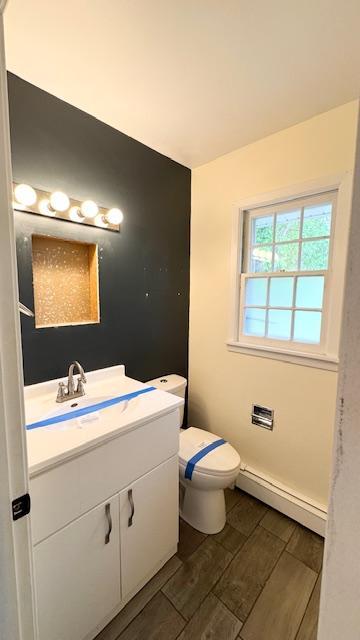 811 Myrtle St, Buffalo, MN 55313 - half bathroom featuring baseboard heating, vanity, wood tiled floors, and vaulted ceiling