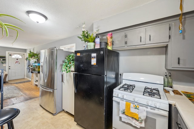 4638 Johnson St NE, Columbia Heights, MN 55421 - kitchen featuring white range with gas cooktop, freestanding refrigerator, stainless steel fridge with ice dispenser, gray cabinetry, and light countertops