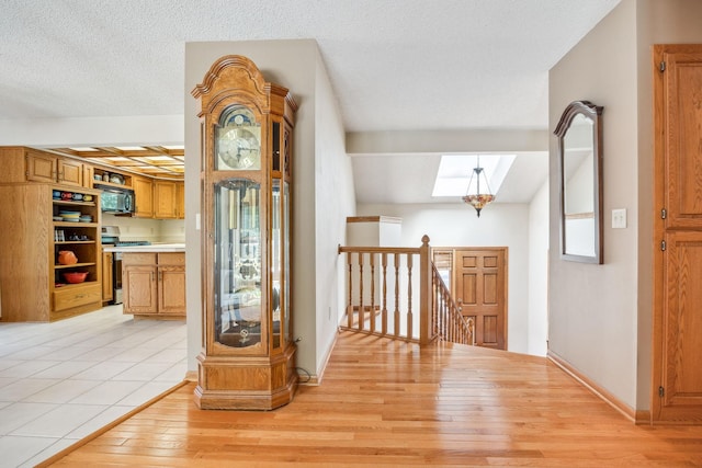 2017 87th Trl N, Brooklyn Park, MN 55443 - hall with an upstairs landing, a skylight, light wood-type flooring, and a textured ceiling