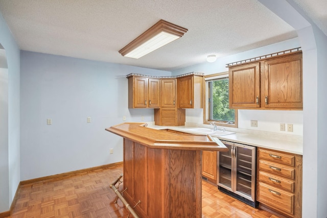 2017 87th Trl N, Brooklyn Park, MN 55443 - kitchen with beverage cooler, a textured ceiling, light countertops, and brown cabinets