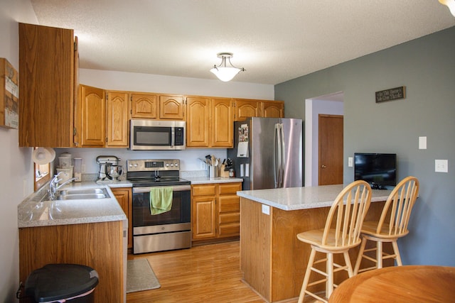 415 3rd St NW, Elgin, MN 55932 - kitchen featuring stainless steel appliances, light wood finished floors, a breakfast bar, and light countertops