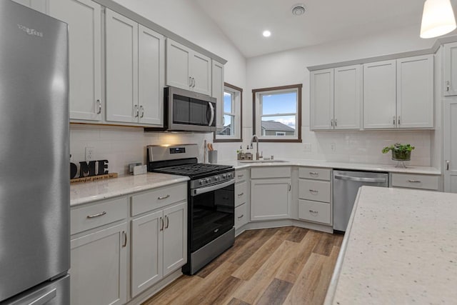 755 Escalade Ln SE, Owatonna, MN 55060 - kitchen with appliances with stainless steel finishes, decorative backsplash, light wood-style floors, recessed lighting, and lofted ceiling