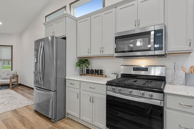 755 Escalade Ln SE, Owatonna, MN 55060 - kitchen with appliances with stainless steel finishes, tasteful backsplash, light wood-style floors, light stone countertops, and lofted ceiling