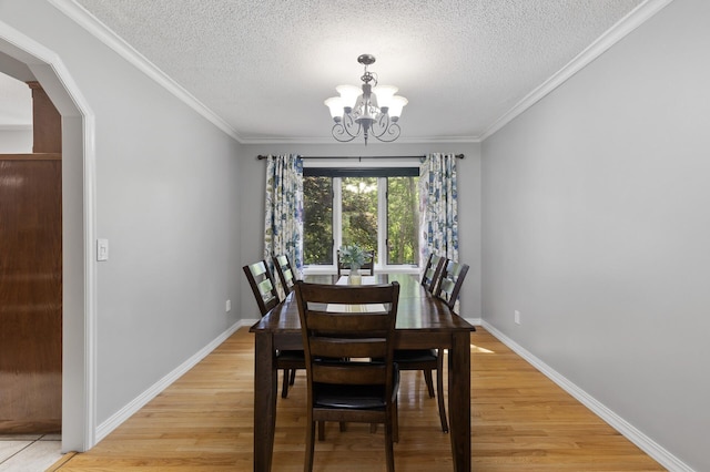 17208 Woodbine St NW, Andover, MN 55304 - dining space featuring a chandelier, a textured ceiling, light wood-style floors, arched walkways, and ornamental molding