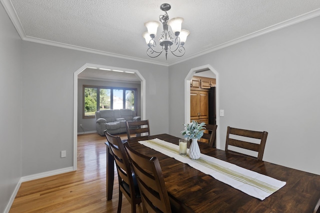 17208 Woodbine St NW, Andover, MN 55304 - dining area with a chandelier, a textured ceiling, arched walkways, light wood finished floors, and crown molding