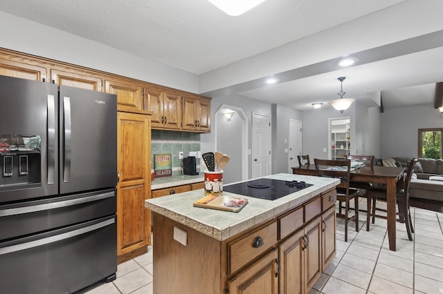 17208 Woodbine St NW, Andover, MN 55304 - kitchen featuring black appliances, light tile patterned floors, brown cabinets, a kitchen island, and pendant lighting