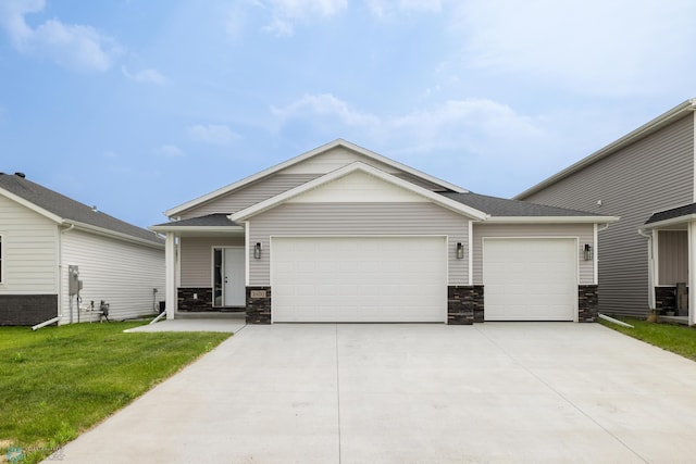 2600 74th Ave S, Fargo, ND 58104 - view of front of house featuring a garage, stone siding, driveway, and a front lawn