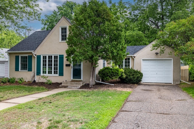 3826 Adair Ave N, Crystal, MN 55422 - view of front facade with a front yard, stucco siding, a garage, a shingled roof, and asphalt driveway
