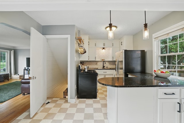3826 Adair Ave N, Crystal, MN 55422 - kitchen with freestanding refrigerator, light floors, white cabinetry, and healthy amount of natural light