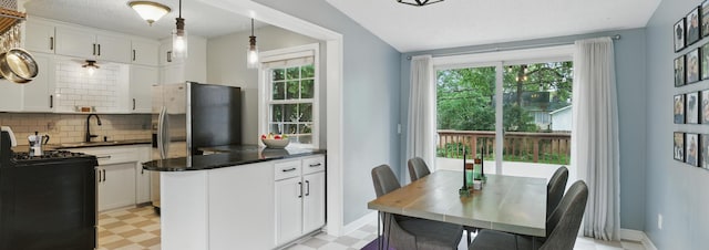 3826 Adair Ave N, Crystal, MN 55422 - kitchen with light floors, dark countertops, tasteful backsplash, and white cabinets