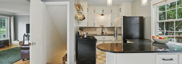 3826 Adair Ave N, Crystal, MN 55422 - kitchen with freestanding refrigerator, white cabinetry, decorative backsplash, and healthy amount of natural light