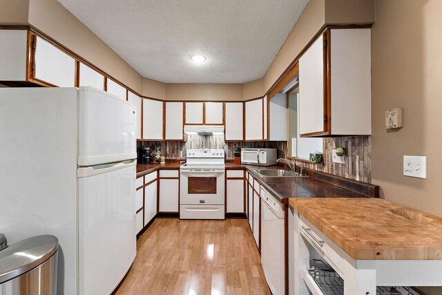 1202 Matteson St, Faribault, MN 55021 - kitchen featuring white appliances, under cabinet range hood, light wood finished floors, white cabinets, and decorative backsplash