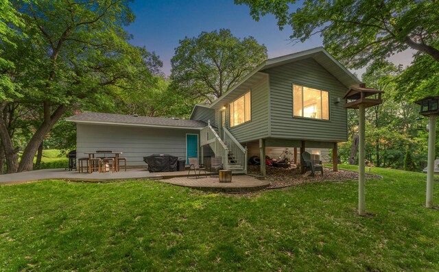 1202 Matteson St, Faribault, MN 55021 - back of house at dusk featuring a patio area, a yard, and stairs