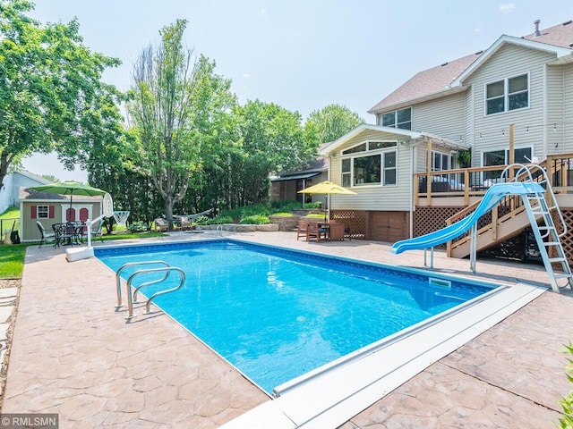 20108 Calgary Trl, Empire Twp, MN 55024 - swimming pool with a wooden deck, a water slide, a patio area, and an outdoor structure