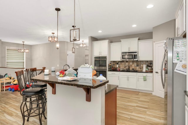 11950 75th St NE, Otsego, MN 55301 - kitchen featuring appliances with stainless steel finishes, a breakfast bar, light wood finished floors, tasteful backsplash, and a chandelier