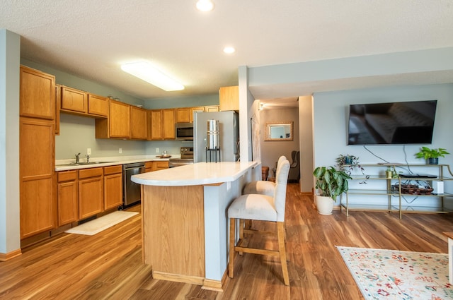 5724 4th St NE, Fridley, MN 55432 - kitchen with stainless steel appliances, light countertops, light wood-type flooring, a breakfast bar area, and a kitchen island