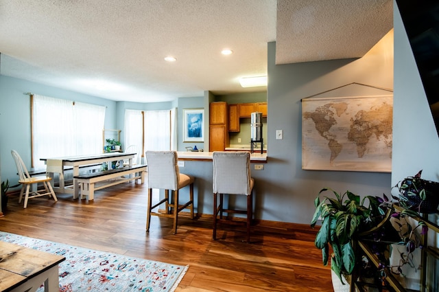 5724 4th St NE, Fridley, MN 55432 - kitchen with a textured ceiling, recessed lighting, wood finished floors, brown cabinetry, and a breakfast bar