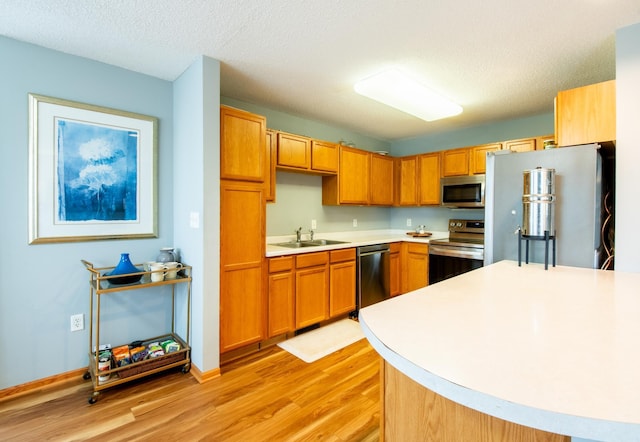 5724 4th St NE, Fridley, MN 55432 - kitchen featuring appliances with stainless steel finishes, light wood-type flooring, light countertops, brown cabinets, and a textured ceiling