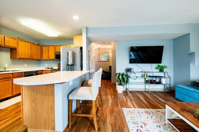 5724 4th St NE, Fridley, MN 55432 - kitchen featuring stainless steel appliances, a kitchen bar, light countertops, light wood-type flooring, and a center island