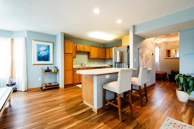 5724 4th St NE, Fridley, MN 55432 - kitchen with freestanding refrigerator, light countertops, light wood-type flooring, a kitchen bar, and recessed lighting