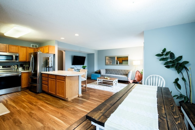 5724 4th St NE, Fridley, MN 55432 - kitchen featuring appliances with stainless steel finishes, open floor plan, a peninsula, wood finished floors, and light countertops