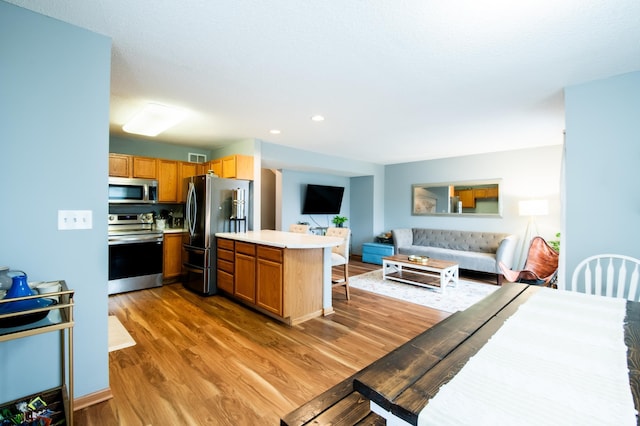 5724 4th St NE, Fridley, MN 55432 - kitchen with stainless steel appliances, open floor plan, light wood-style floors, light countertops, and a breakfast bar