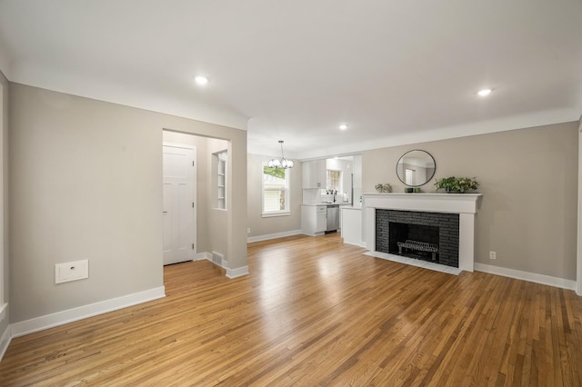 5644 Upton Ave S, Minneapolis, MN 55410 - unfurnished living room featuring light wood-type flooring, a chandelier, a brick fireplace, and recessed lighting