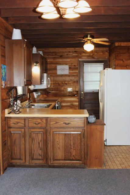 47393 209th Pl, Mcgregor, MN 55760 - kitchen with freestanding refrigerator, light countertops, light carpet, brown cabinets, and wooden walls