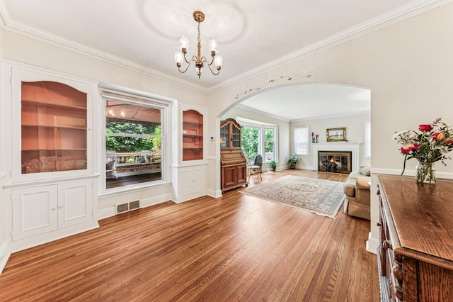 3703 Beard Ave N, Robbinsdale, MN 55422 - living area featuring arched walkways, wood finished floors, ornamental molding, a chandelier, and a glass covered fireplace