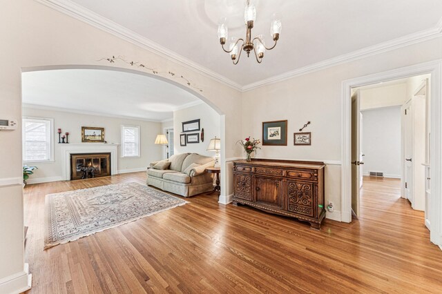 3703 Beard Ave N, Robbinsdale, MN 55422 - living room featuring arched walkways, wood finished floors, a chandelier, crown molding, and a glass covered fireplace