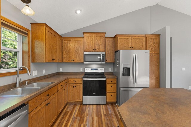 527 1st Ave NE, Lonsdale, MN 55046 - kitchen featuring appliances with stainless steel finishes, lofted ceiling, wood finished floors, brown cabinetry, and dark countertops