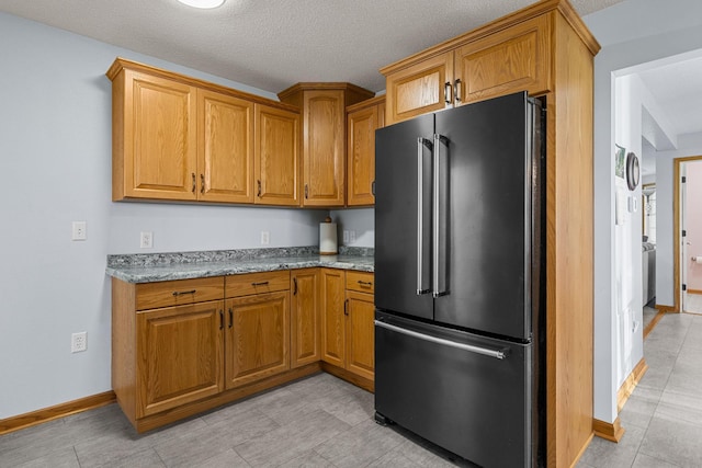 4193 Austin Rd, Owatonna, MN 55060 - kitchen featuring high end fridge, brown cabinetry, light stone counters, a textured ceiling, and light tile patterned floors