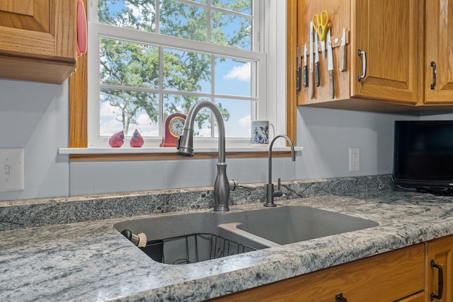 4193 Austin Rd, Owatonna, MN 55060 - kitchen featuring brown cabinetry, plenty of natural light, and light stone counters