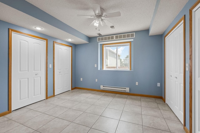 4193 Austin Rd, Owatonna, MN 55060 - unfurnished bedroom featuring a baseboard heating unit, multiple closets, a textured ceiling, light tile patterned flooring, and a ceiling fan