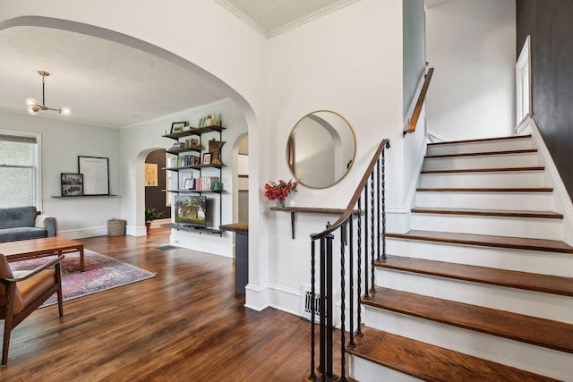 4210 Blaisdell Ave, Minneapolis, MN 55409 - staircase featuring crown molding, arched walkways, wood finished floors, and a chandelier