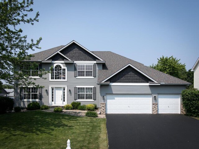 2074 Ormond Dr, Shakopee, MN 55379 - view of front facade featuring driveway, a garage, a front yard, and a shingled roof
