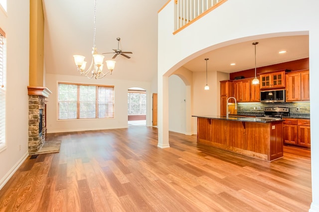 10725 Toledo Ln N, Brooklyn Park, MN 55443 - kitchen with appliances with stainless steel finishes, open floor plan, brown cabinetry, a kitchen bar, and a towering ceiling
