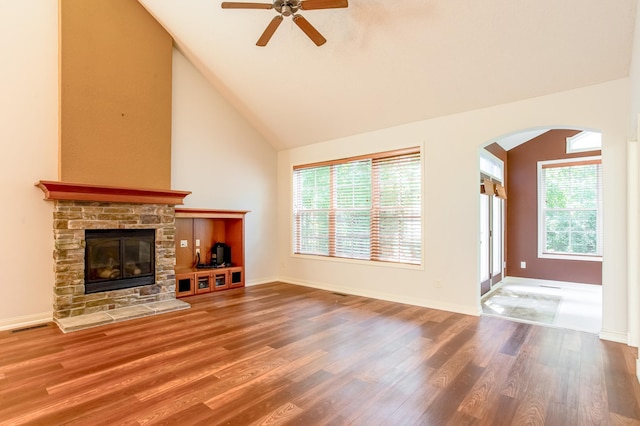 10725 Toledo Ln N, Brooklyn Park, MN 55443 - unfurnished living room with arched walkways, ceiling fan, wood finished floors, a stone fireplace, and high vaulted ceiling