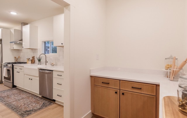 212 Diamond Lake Rd, Minneapolis, MN 55419 - kitchen featuring stainless steel appliances, light countertops, wall chimney range hood, light wood finished floors, and decorative backsplash