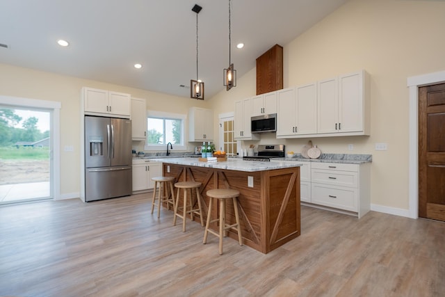 kitchen featuring stainless steel appliances, high vaulted ceiling, a breakfast bar area, white cabinetry, and a kitchen island