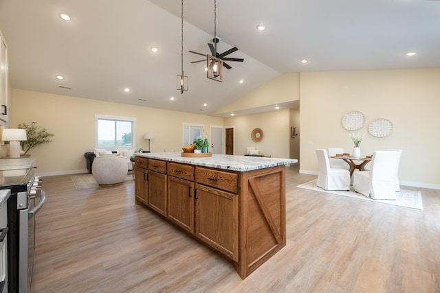 kitchen featuring a ceiling fan, brown cabinets, open floor plan, stainless steel range oven, and lofted ceiling
