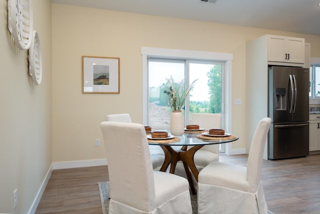 dining space featuring light wood-style flooring and baseboards