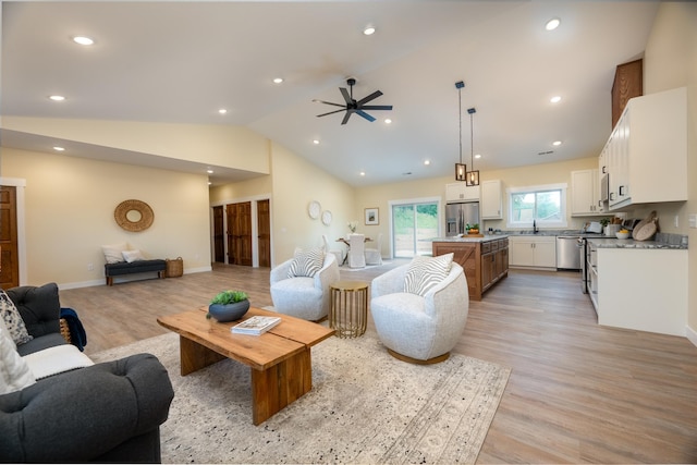 living room featuring vaulted ceiling, a ceiling fan, light wood-style flooring, and recessed lighting